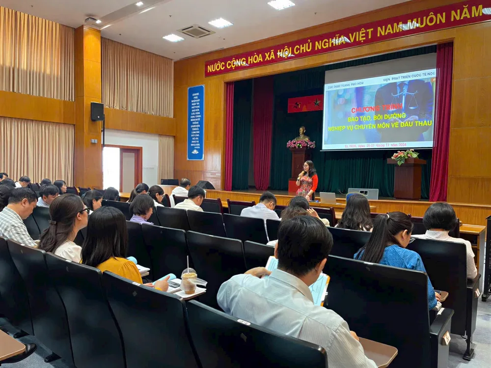 Nữ giảng viên trình bày nội dung bên bục phát biểu, phía dưới là đông đảo học viên tham dự tại hội trường đào tạo.