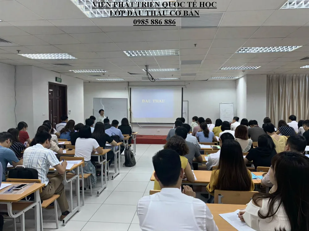 Học viên lớp đấu thầu cơ bản ngồi theo dãy bàn, hướng lên màn hình trình chiếu nội dung bài giảng.